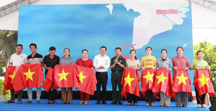 Thượng tá Trần Doãn Toản, Chính trị viên Đồn Biên phòng Sơn Trà và Chánh Văn phòng UBND đặc khu Hoàng Sa, Giám đốc Nhà trưng bày Hoàng Sa Lê Tiến Công trao tặng cờ Tổ quốc và quà cho ngư dân. Ảnh: ĐẮC MẠNH