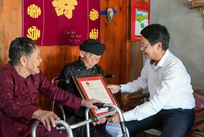 Phó Bí thư Thành ủy Ngô Xuân Thắng trao thiếp mừng thọ 100 tuổi của Chủ tịch nước cho cụ Đoàn Em. Ảnh: HỒ QUÂN