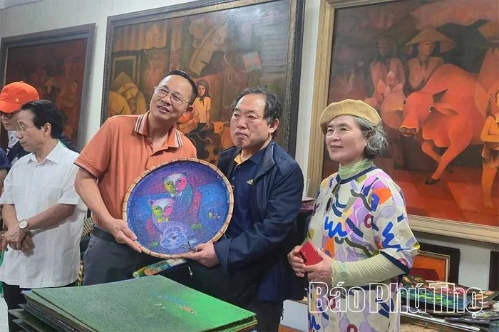 Họa sĩ Hoàng Trúc tặng tranh vẽ trên chiếc mẹt tre cho các thành viên Hiệp hội Giao lưu Mỹ thuật Quốc tế Hàn Quốc.