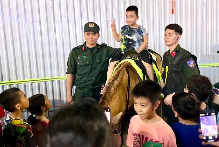 Các em nhỏ chụp hình lưu niệm cùng cán bộ, chiến sĩ Đoàn Cảnh sát cơ động Kỵ binh tại buổi diễu hành tối 4/6