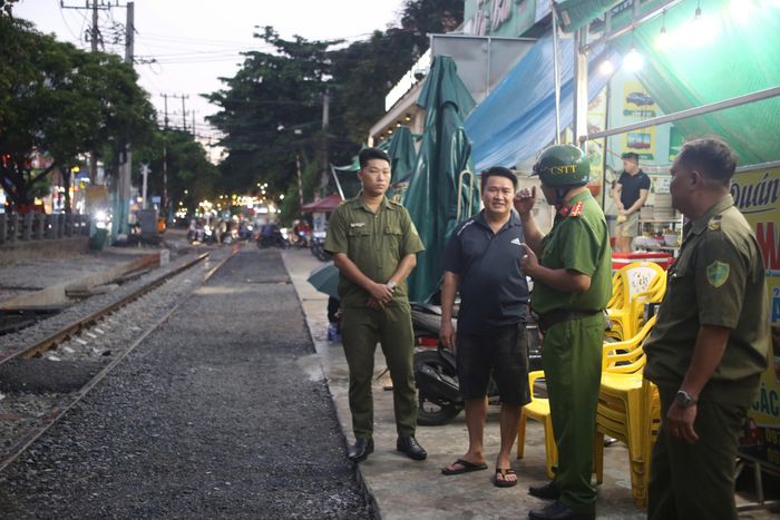  Công an phường Dĩ An tuyên truyền, nhắc nhở các hộ kinh doanh không bày bán hàng hóa, đặt vật dụng lấn chiếm hành lang an toàn đường sắt. Hoạt động này nhận được sự đồng tình, ủng hộ của nhiều người dân và hộ buôn bán trên địa bàn. Ảnh: PHẠM HẢI 