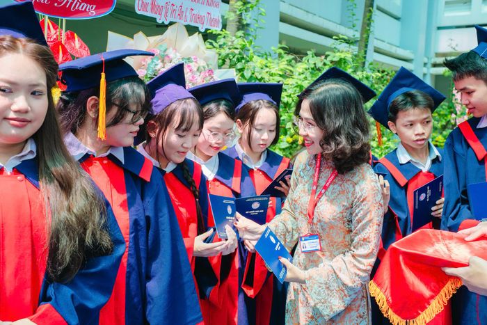 Cô Lê Thị Hồng Anh, Phó Hiệu trưởng tặng tấm "hộ chiếu vào đời" cho các em học sinh. Ảnh: NTCC