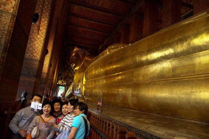  Nhóm du khách Trung Quốc chụp ảnh cạnh tượng Phật nằm tại chùa Wat Pho ở Bangkok, Thái Lan, năm 2016. Ảnh: Reuters. 