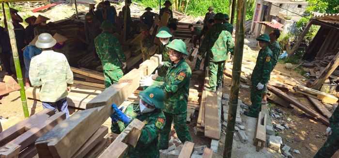 Cán bộ, chiến sĩ Trung tâm Huấn luyện - Cơ động Tây Bắc phối hợp cùng người dân tháo dỡ, vận chuyển các cấu kiện nhà ở đến nơi ở mới. Ảnh: Nghĩa Hà