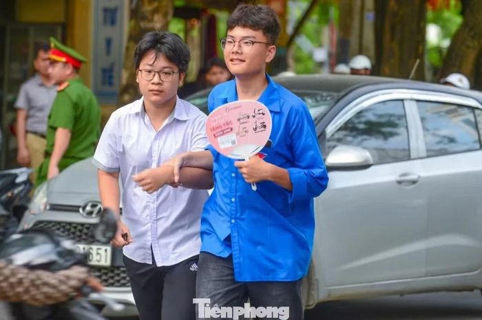 Tình nguyện viên dắt tay đưa sĩ tử qua đường, động viên trước giờ thi.
