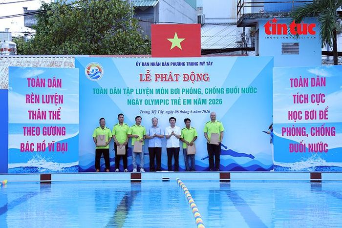 Lãnh đạo phường Trung Mỹ Tây trao dụng cụ giảng dạy bơi cho các huấn luyện viên.