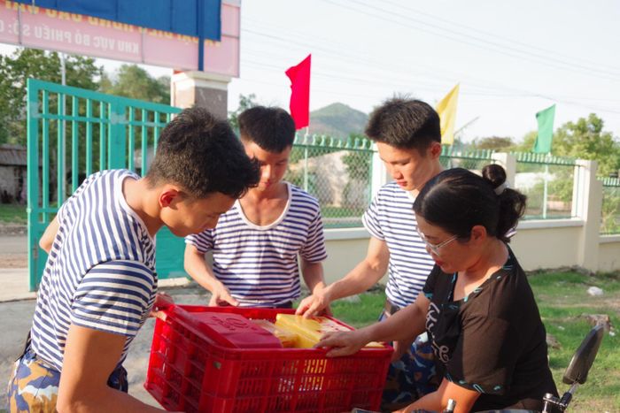 Các học viên phụ giúp đưa các phần cơm đến địa điểm nghi ngơi của đơn vị. Ảnh: Huy Tứ