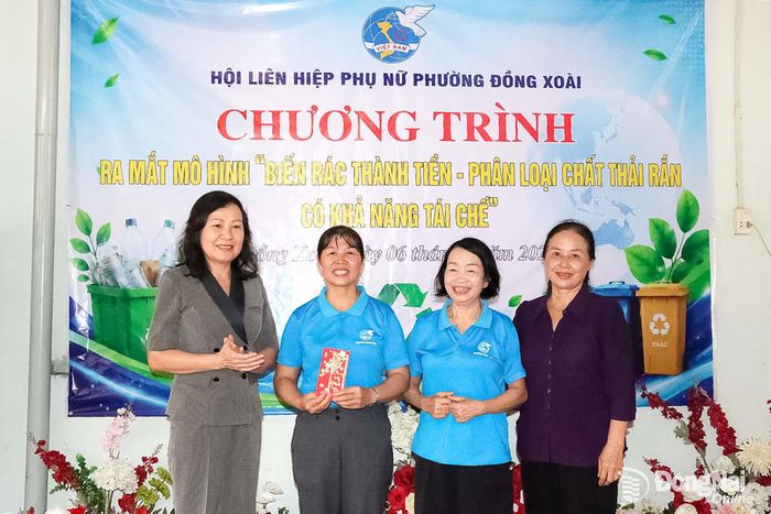 Phó Bí thư Thành ủy, Chủ tịch Ủy ban MTTQ Việt Nam thành phố Huỳnh Thị Hằng tặng quà cho Mô hình “Biến rác thải thành tiền - Phân loại rác thải rắn có khả năng tái chế”, tại khu phố Tân Thành 2, phường Đồng Xoài. Ảnh: Quang Minh