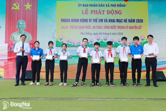 Phó Bí thư Đảng ủy, Chủ tịch UBND xã Nguyễn Danh Tùng trao quà cho học sinh vượt khó học giỏi. Ảnh: Vũ Nguyện