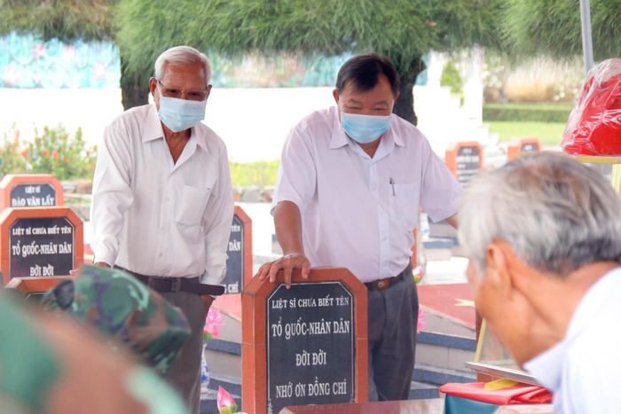 Ông Hoàng Long, Trưởng Ban Liên lạc kháng chiến Hoài Đức - Đức Linh (bìa trái) theo dõi công tác lấy mẫu hài cốt liệt sĩ tại Nghĩa trang Liệt sĩ Đức Linh, Lâm Đồng