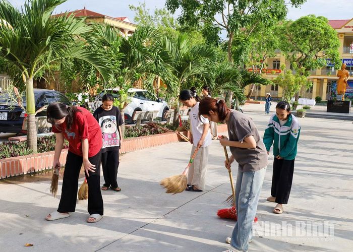 Các em học sinh Trường THCS An Lão quét dọn khu vực cổng trường. Ảnh: Phạm Hiền