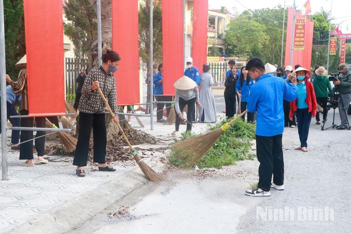 Các đoàn viên, hội viên tham gia quét dọn đường trục chính của xã. Ảnh: Phùng Thống