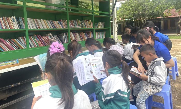 Đoàn viên, thanh niên hướng dẫn các em học sinh đọc sách tại thư viện lưu động - Ảnh: K.H
