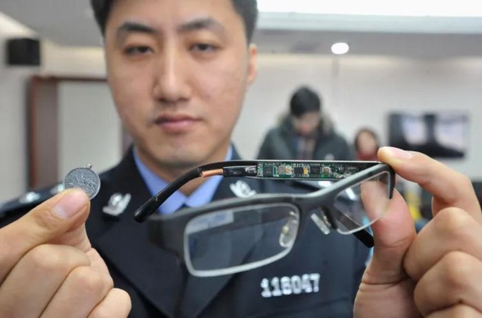 Cảnh sát thu giữ một cặp kính có gắn camera ẩn và một bộ thu tín hiệu nhỏ gắn vào một đồng xu tại một địa điểm thi ở Thẩm Dương, tỉnh Liêu Ninh, Trung Quốc. Ảnh: Reuters