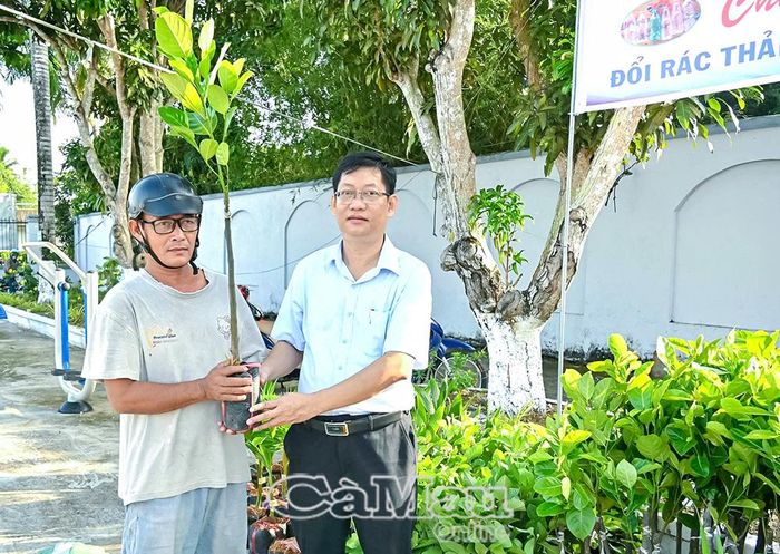  Đồng chí Nguyễn Thanh Hoàng, Chủ tịch UBND xã Vĩnh Phước (bìa phải), tặng cây ăn trái đổi rác thải nhựa cho người dân địa phương.