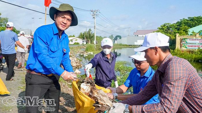 Anh Trần Đăng Khoa (bìa trái) tham gia hoạt động bảo vệ môi trường cùng đoàn viên, thanh niên tại ấp Đường Kéo.