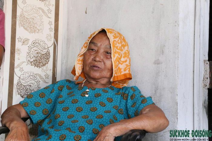 Bà Đặng Thị Ba dùng khăn ướt đắp lên đầu để giảm bớt cảm giác oi bức trong những ngày nắng nóng.