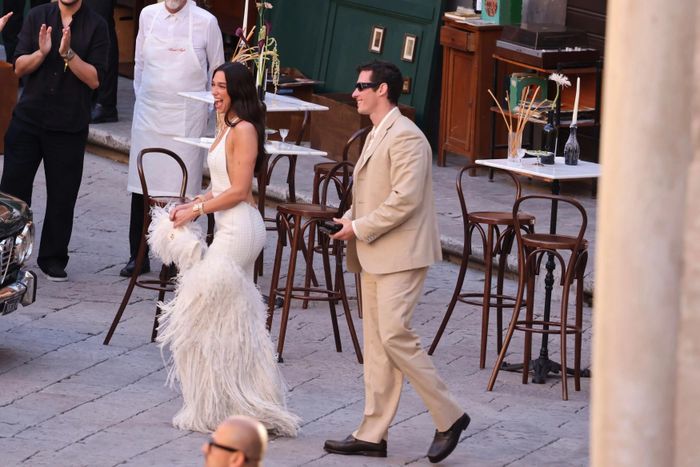 Dua Lipa khởi động chuỗi hoạt động mừng đám cưới cùng chồng Callum Turner bằng buổi tiệc chào đón tại Sicily (Italy) trong tuần qua. Nữ ca sĩ 30 tuổi lựa chọn thiết kế riêng của Bottega Veneta với chất liệu da đan thủ công màu trắng, chi tiết xẻ sâu phía sau lưng và chân váy tua rua đính lông vũ. Cô kết hợp trang phục với clutch Andiamo đồng điệu cùng nhiều món trang sức cao cấp từ Bulgari. Ảnh: Backgrid.