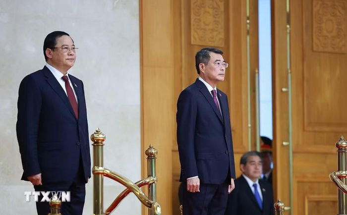 Thủ tướng Lê Minh Hưng và Thủ tướng Lào Sonexay Siphandone nghe Quân nhạc cử Quốc thiều hai nước. (Ảnh: Dương Giang/TTXVN)