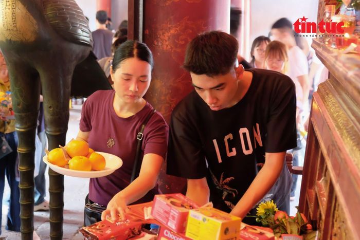 Một sĩ tử được mẹ giúp đỡ sắp xếp đồ lễ lên ban thờ một cách cẩn thận.