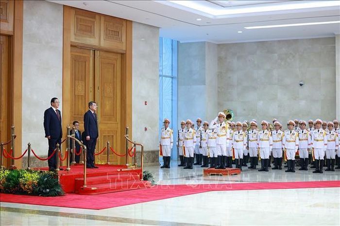 Thủ tướng Lê Minh Hưng và Thủ tướng Lào Sonexay Siphandone nghe Quân nhạc cử Quốc thiều hai nước. Ảnh: Dương Giang/TTXVN.