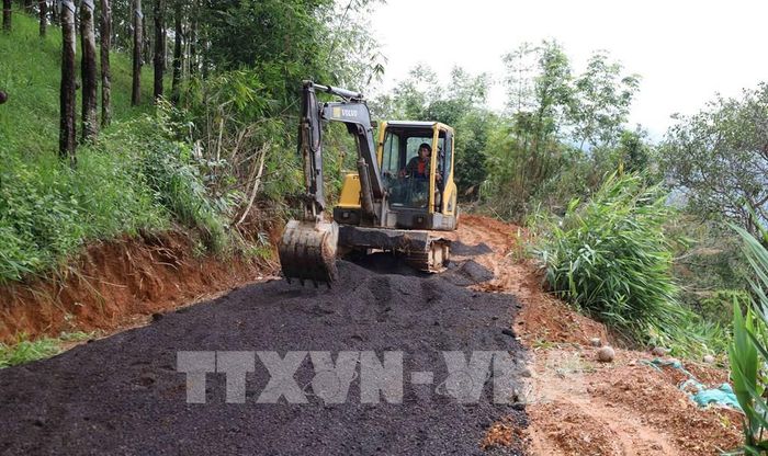 Mỗi hộ gia đình đóng ít nhất 3 triệu đồng để thuê máy múc san gạt mặt bằng, đào mương thoát nước, đổ đá dăm gia cố các đoạn đường xuống cấp nghiêm trọng. Ảnh: Đậu Tất Thành – TTXVN