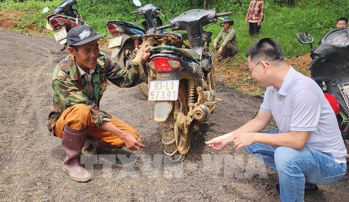 Anh Nguyễn Thanh Văn (đội nón bên trái), thôn Sơn Phú, xã Thọ Sơn, thành phố Đồng Nai cho biết, mùa mưa, anh Văn phải lắp xích chống trượt vào bánh xe mới lưu thông được qua tuyến đường Bà Lan. Ảnh: Đậu Tất Thành – TTXVN