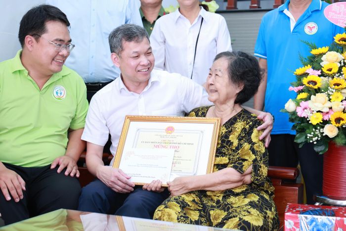 Thiếu tướng Tạ Văn Đẹp thay mặt Thành ủy, HĐND, UBND và Ủy ban MTTQ Việt Nam TPHCM tặng quà chúc thọ cụ Trầm Thị Huệ