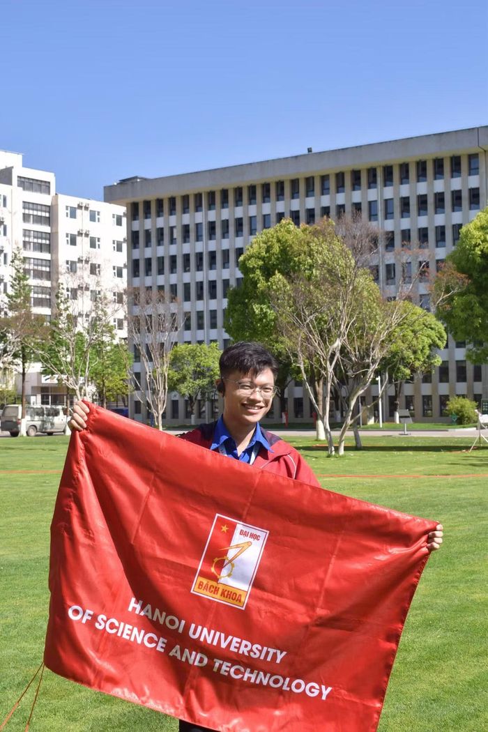 Đình Đạo vinh dự cầm cờ Đại học Bách khoa Hà Nội chụp ảnh lưu niệm tại Đại học Liên hợp Tây Nam.