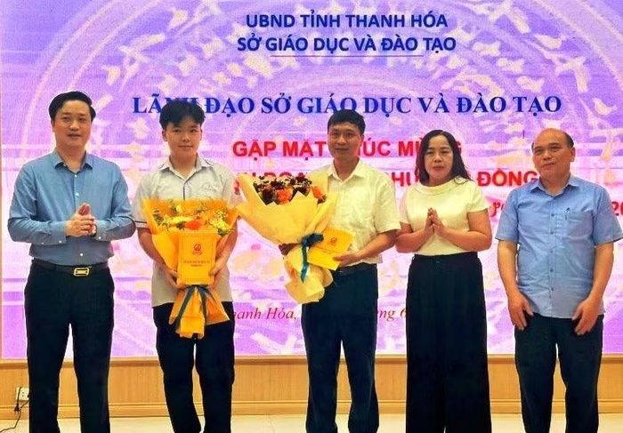 Em Nguyễn Bảo Khánh và thầy giáo Nguyễn Văn Nhiệm - giáo viên trực tiếp giảng dạy môn Toán, được lãnh đạo Sở GD&ĐT Thanh Hóa tặng hoa.