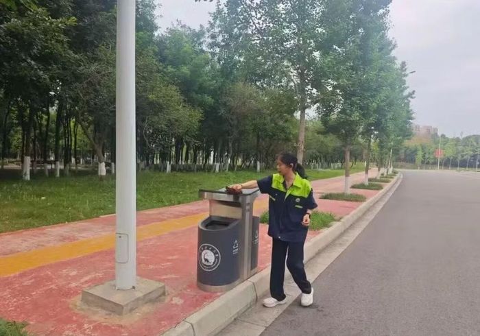 Cô Li dọn dẹp thùng rác trong khuôn viên trường. Ảnh: Baidu