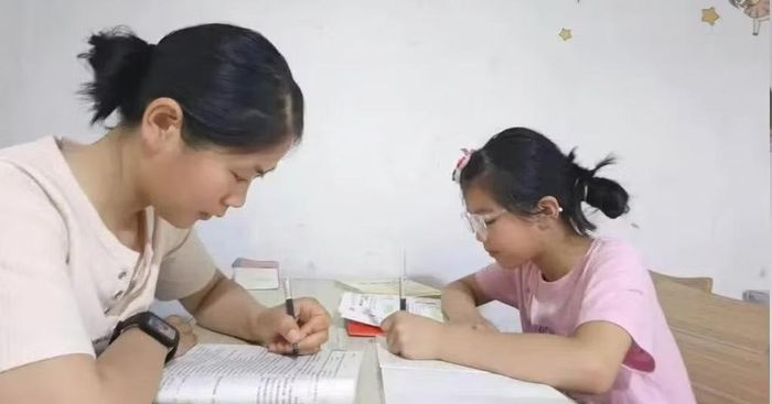 Li chăm chỉ học cùng con gái đang làm bài tập về nhà. Ảnh: Baidu