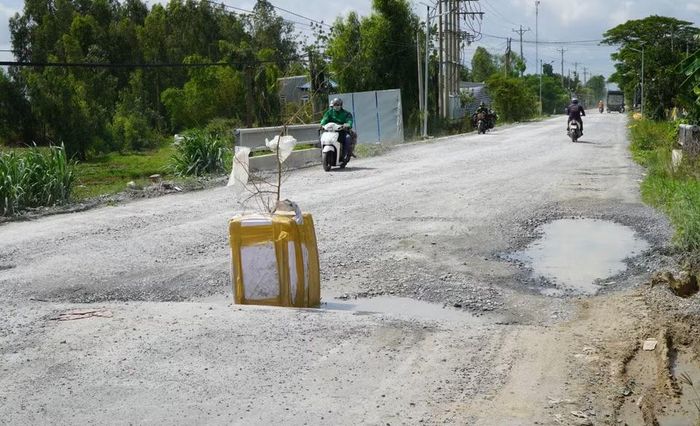 Người dân đặt vật cảnh báo giúp người tham gia giao thông né “ổ gà” trên Quốc lộ 30 đoạn qua xã Tân Hồng. (Ảnh: Nhựt An/TTXVN)