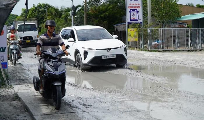 Người dân phải chạy xe gắn máy trên cống thoát nước để né những hố to bùn lầy trên Quốc lộ 30 đoạn qua ấp Gò Da, xã Tân Hồng. (Ảnh: Nhựt An/TTXVN)