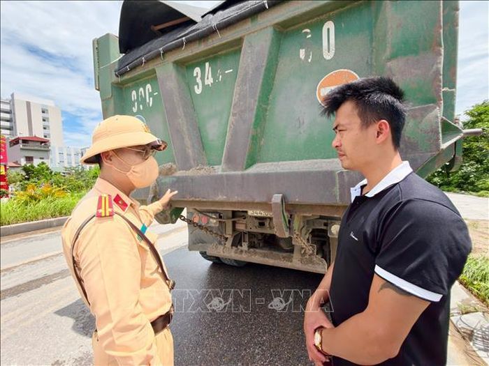 Cán bộ Cảnh sát giao thông tuyên truyền, nhắc nhở và làm việc với đại diện doanh nghiệp vận tải về trách nhiệm bảo đảm tải trọng, che chắn hàng hóa và vệ sinh môi trường trong quá trình vận chuyển vật liệu xây dựng. Ảnh: Trung Nguyên/TTXVN
