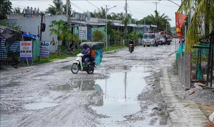 Người và phương tiện vất vả đi qua Quốc lộ 30 đoạn thuộc địa bàn ấp Gò Da, xã Tân Hồng (tỉnh Đồng Tháp).