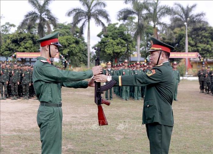 Trung tá Nguyễn Văn Lượng, Trung đoàn trưởng Trung đoàn Bộ binh 24, thực hiện nghi thức trao súng cho chiến sĩ mới tại Lễ tuyên thệ chiến sĩ mới năm 2026. Ảnh: Hoàng Hùng/TTXVN