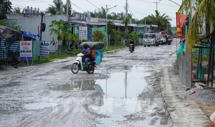 Người và phương tiện vất vả đi qua Quốc lộ 30 đoạn thuộc địa bàn ấp Gò Da, xã Tân Hồng (tỉnh Đồng Tháp). Ảnh: Nhựt An - TTXVN