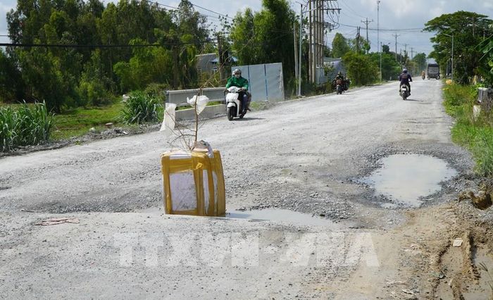 Người dân đặt vật cảnh báo giúp người tham gia giao thông né “ổ gà” trên Quốc lộ 30 đoạn qua xã Tân Hồng. Ảnh: Nhựt An - TTXVN