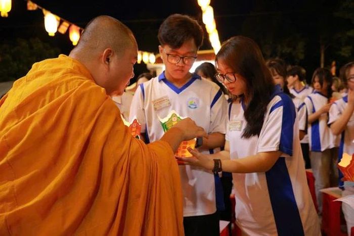 Các em học sinh thành kính đón nhận ánh sáng hoa đăng từ chư tôn đức
