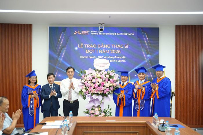Đại diện tân thạc sĩ tặng hoa tri ân lãnh đạo Nhà trường và các đơn vị đồng hành