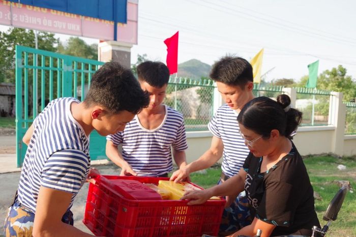 Các học viên phụ giúp đưa các phần cơm đến địa điểm nghi ngơi của đơn vị.