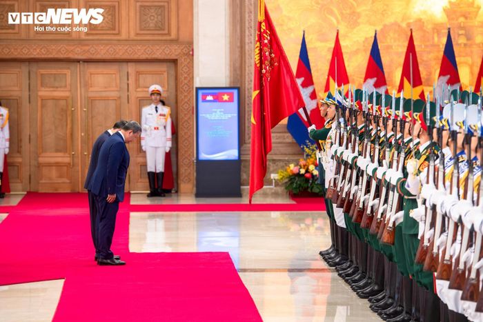 Thủ tướng Lê Minh Hưng và Thủ tướng Vương quốc Campuchia Samdech Moha Borvor Thipadei Hun Manet cúi chào Quân kỳ Quyết thắng của Quân đội Nhân dân Việt Nam.