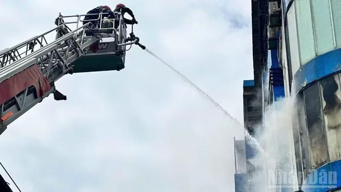 Lính cứu hỏa phun nước từ độ cao trên tầng 4 tòa nhà. (Ảnh: ANH ĐÀO)