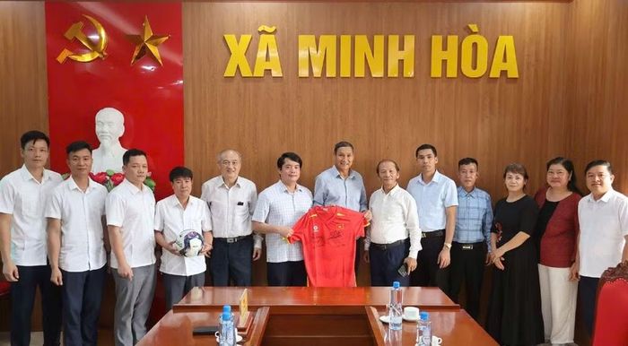 HLV Mai Đức Chung tặng bóng và áo đấu có chữ ký của cầu thủ cho lãnh đạo xã Minh Hòa.
