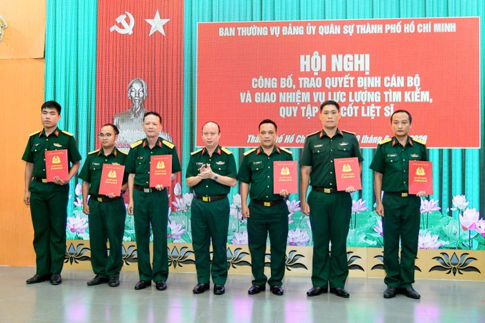 Đại tá Nguyễn Đình Chuẩn, Phó Chính ủy Bộ Tư lệnh TPHCM trao quyết định điều động, bổ nhiệm cho 6 đồng chí tham gia lực lượng tìm kiếm, quy tập hài cốt liệt sĩ. Ảnh: HỮU TÂN
