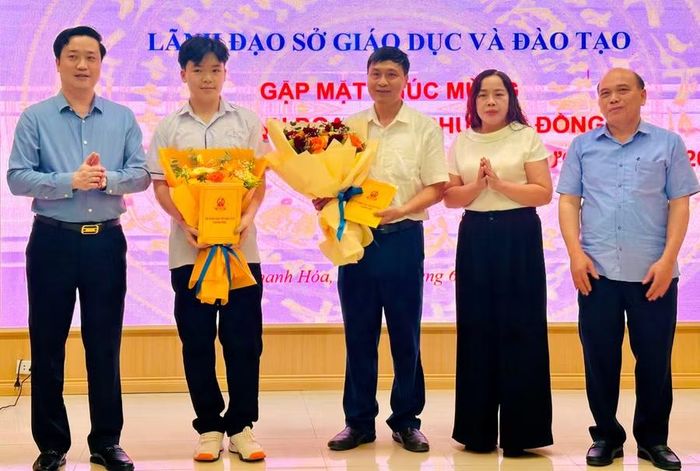 Nam sinh Nguyễn Bảo Khánh và thầy giáo Nguyễn Văn Nhiệm được lãnh đạo Sở GD&ĐT Thanh Hóa tặng hoa chúc mừng.