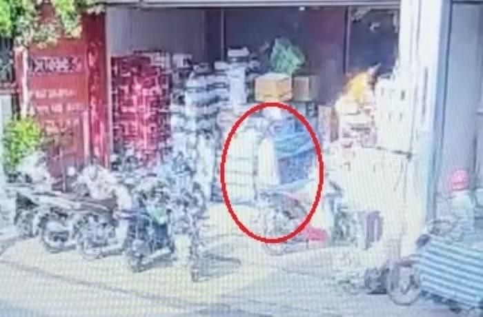 Nghi phạm đổ dung dịch nghi là xăng vào hàng hóa sau đó châm lửa. Khi thấy lửa bùng lên nghi phạm mới ra xe máy rời đi. Ảnh cắt từ clip.