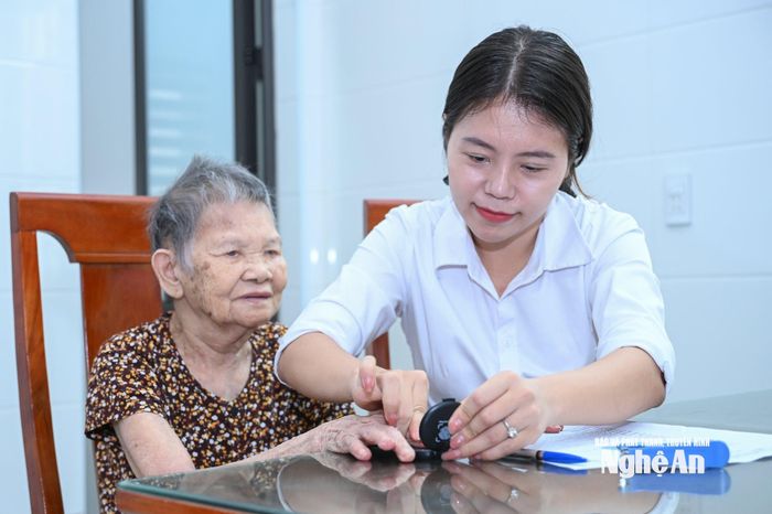 Cán bộ Trung tâm Phục vụ hành chính công làm thủ tục lăn tay, chứng thực chữ ký cho bà Nguyễn Thị Khiêm, xóm Hồ Sơn, xã Vạn An. Ảnh: Thành Cường