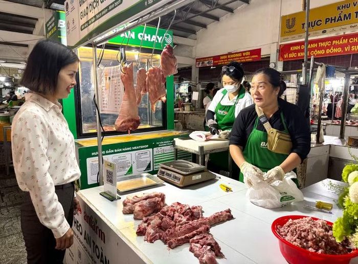 Đại diện phường Tân Mỹ trò chuyện với tiểu thương tham gia bán thịt "Tick xanh trách nhiệm" tại chợ Tân Mỹ, Thành phố Hồ Chí Minh. (Ảnh: Hương Giang/TTXVN)